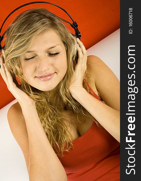 Young Girl loves listening to music with headphones sitting on the sofa. Young Girl loves listening to music with headphones sitting on the sofa