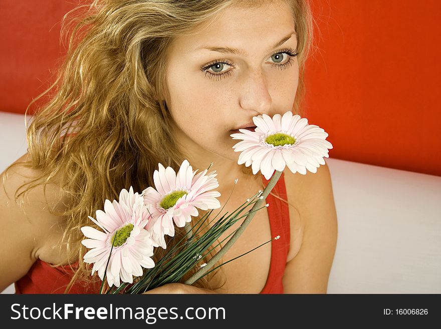 Beautiful girl at home sitting on the couch with flowers gerbera. Beautiful girl at home sitting on the couch with flowers gerbera