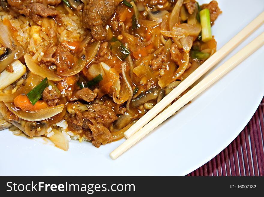 Plate of chinese beef and oyster sauce on purple bamboo place mat and chopsticks. Plate of chinese beef and oyster sauce on purple bamboo place mat and chopsticks