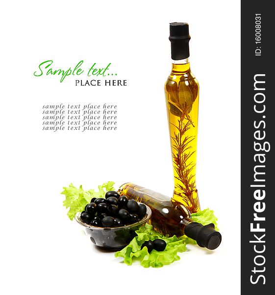 A bottle of olive oil with herbs and black olives