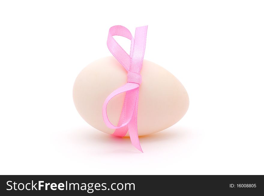 White egg wrapped around with pink ribbon over white background. White egg wrapped around with pink ribbon over white background