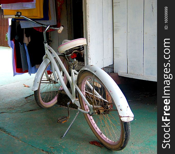 An old distressed girly bicycle in white and pink waiting to be used. An old distressed girly bicycle in white and pink waiting to be used