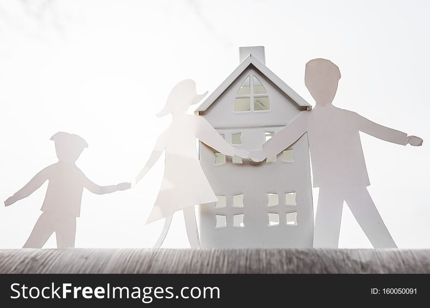 Family concept. Paper origami of father, mother and son hold hands against home. Parents and child near house