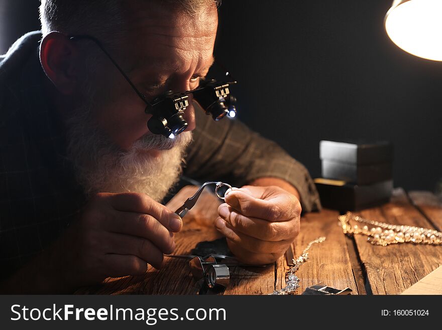 Male jeweler evaluating diamond ring in workshop