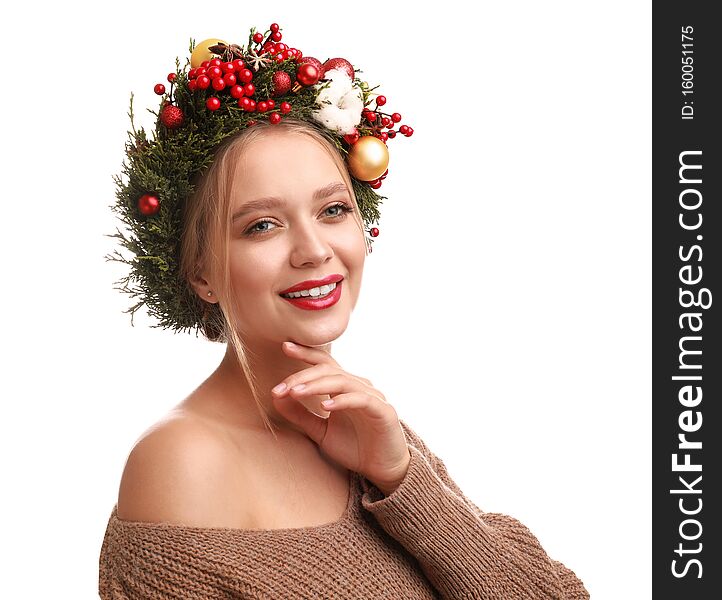 Beautiful young woman wearing Christmas wreath on background