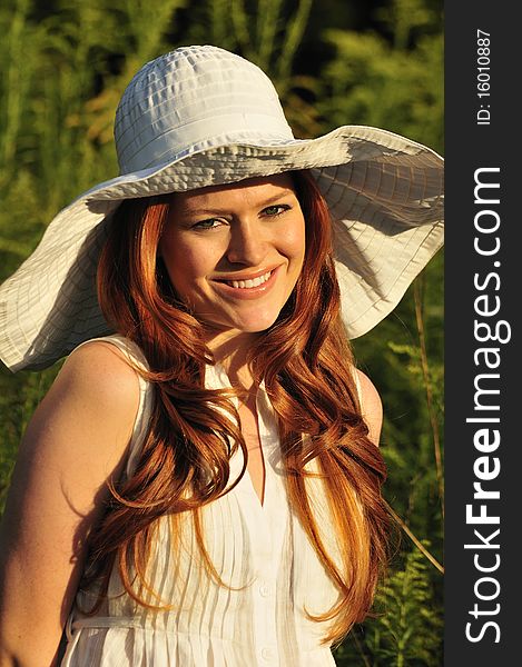 Portrait of a beautiful redhead with a white wide brim sun hat. Portrait of a beautiful redhead with a white wide brim sun hat