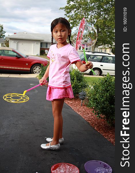 Cute Asian girl playing with a bubble wand. Cute Asian girl playing with a bubble wand.