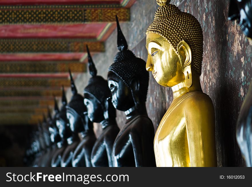 Golden Buddha between black Buddhas