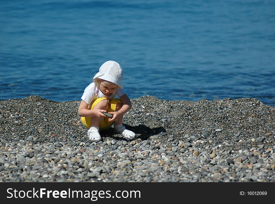 Small Child Sits On Seaside