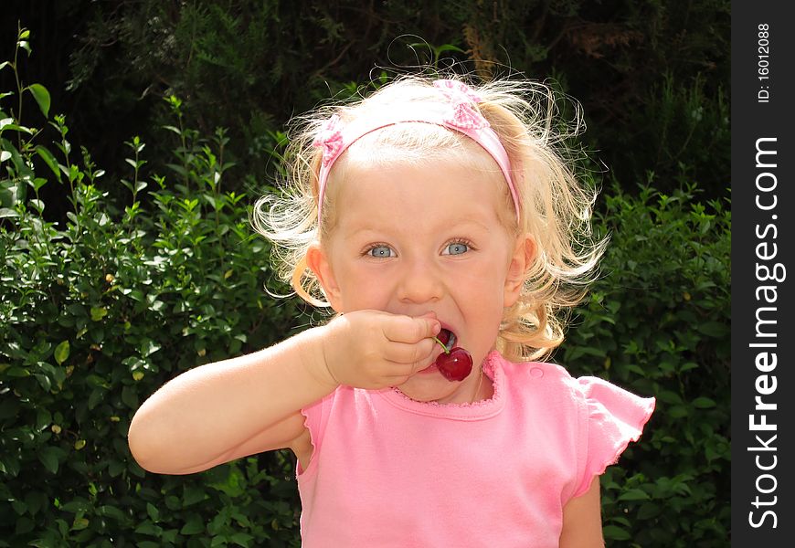 Little girl eats cherry