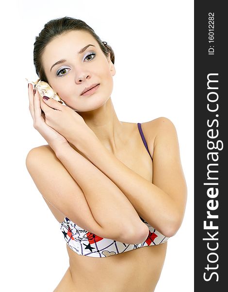 Young fashion model posing in swimsuit isolated on white listening to a seashell