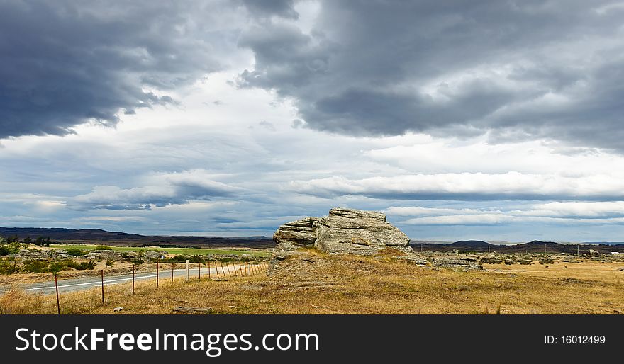 A rocky outcrop juts out of the Strath Taeri plains in the Maniototo, South Island, New Zealand