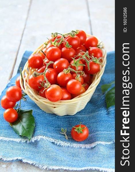 A lot of cherry tomatoes in basket on wooden table. A lot of cherry tomatoes in basket on wooden table