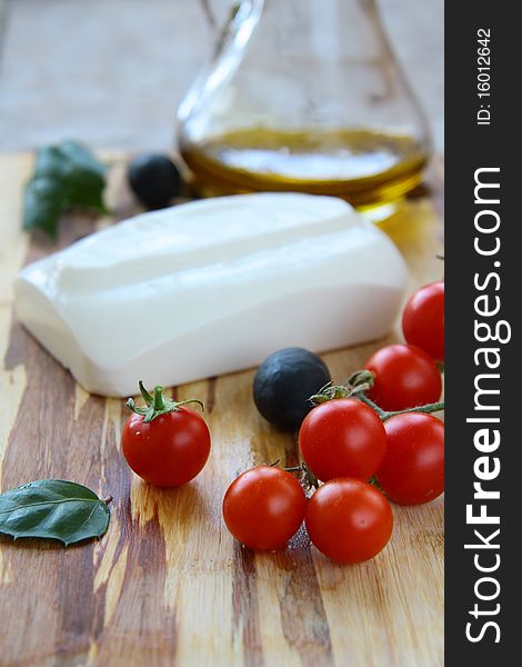 Cheese, tomatoes and olive oil on a wooden board