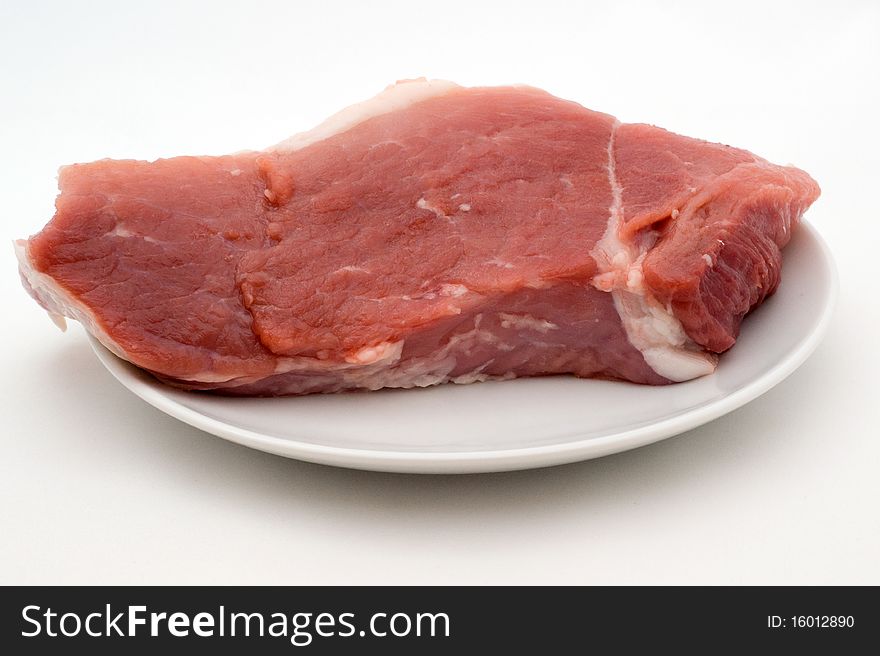 A piece of fresh raw meat on a plate on a white background in isolation