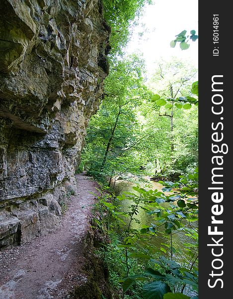 Hiking trail between cliff, rocks and river