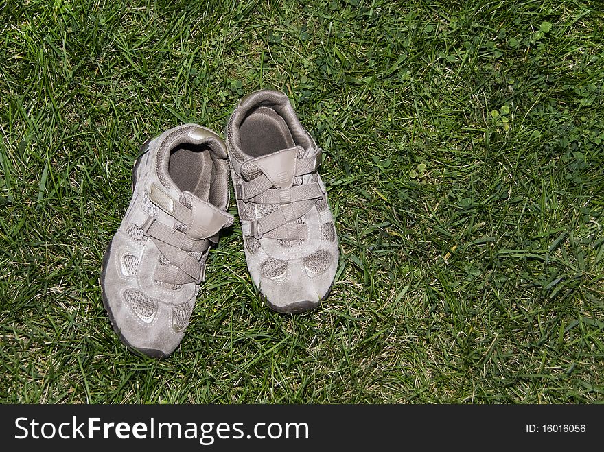 A pair of tennis shoes left on the green grass. A pair of tennis shoes left on the green grass.