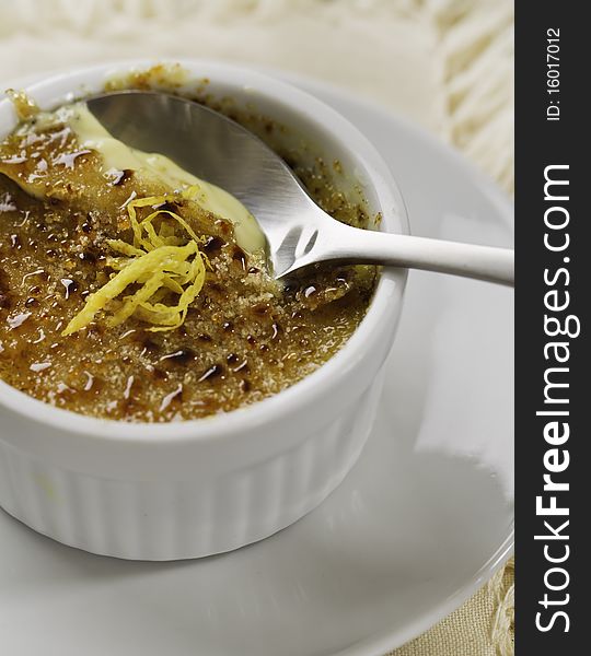 Creme brulee desert on white plate with a spoon. French culture cuisine.