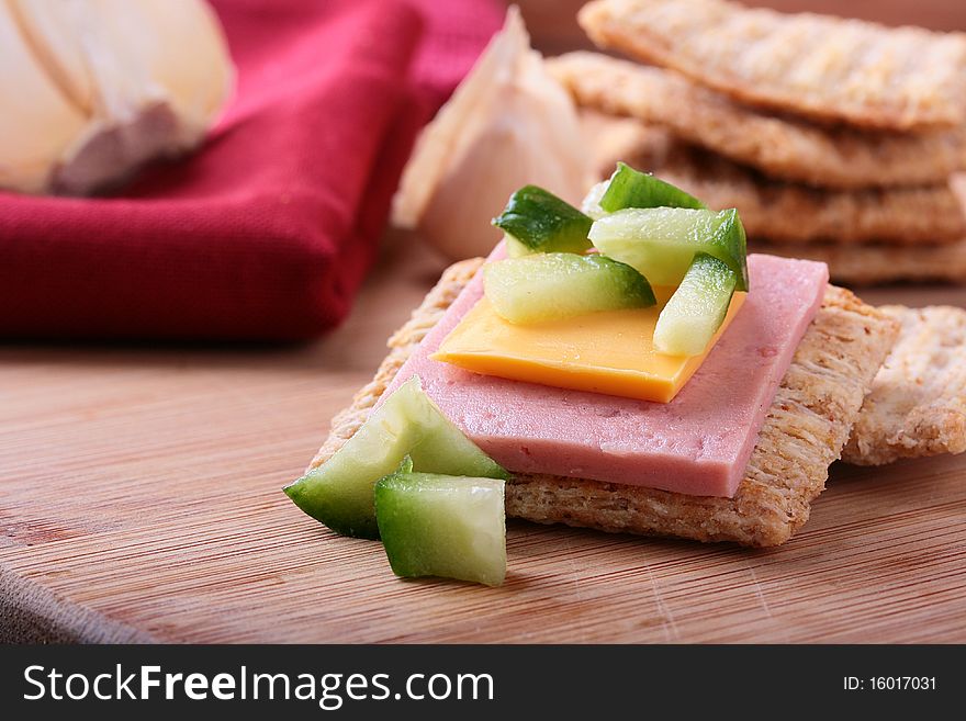 Wheat crackers on a kitchen board with cheese and cucumber. Wheat crackers on a kitchen board with cheese and cucumber.