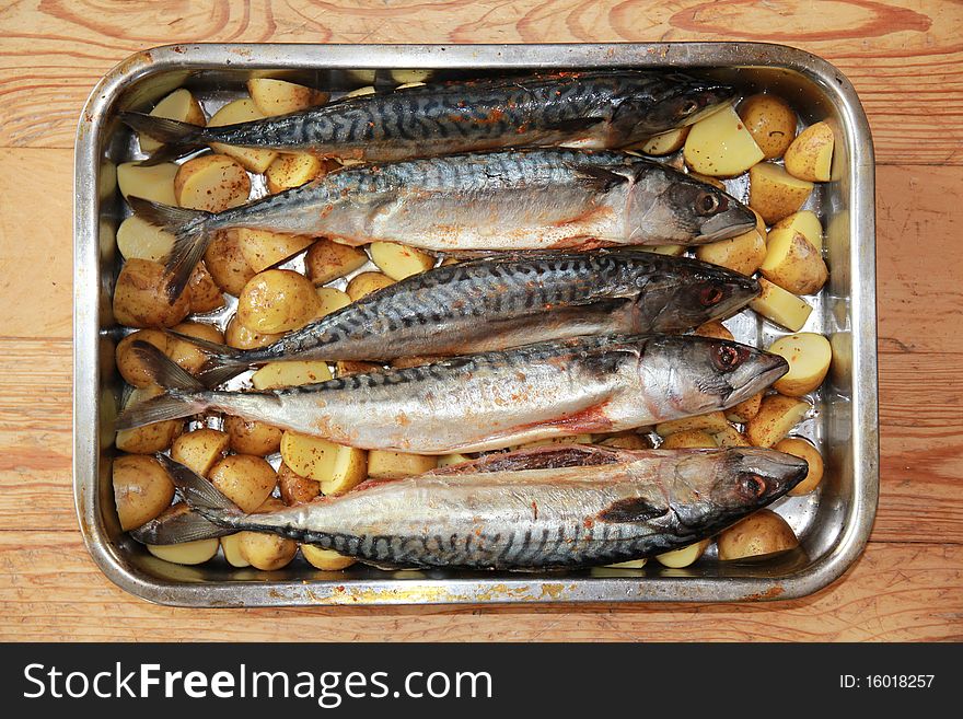 Uncooked fish with potatoes in pan ready to be roast