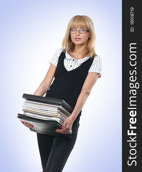 A young and cute business woman in formal clothes is holding a large pack of books. The image is isolated on a light blue gradient background. A young and cute business woman in formal clothes is holding a large pack of books. The image is isolated on a light blue gradient background.