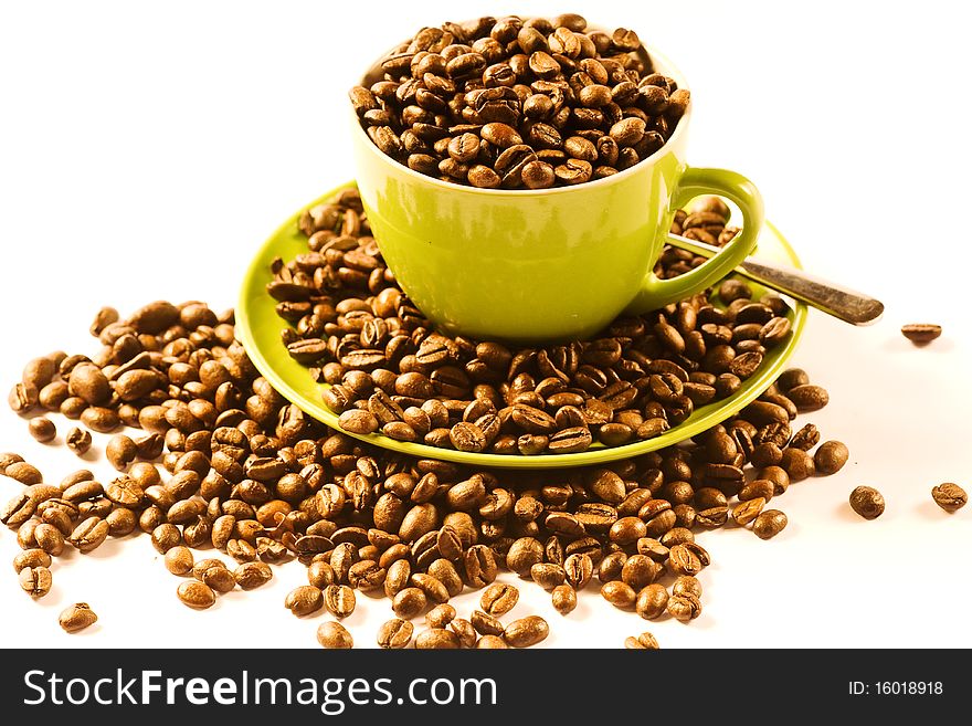 Green cup of coffee with brown beans on white ground