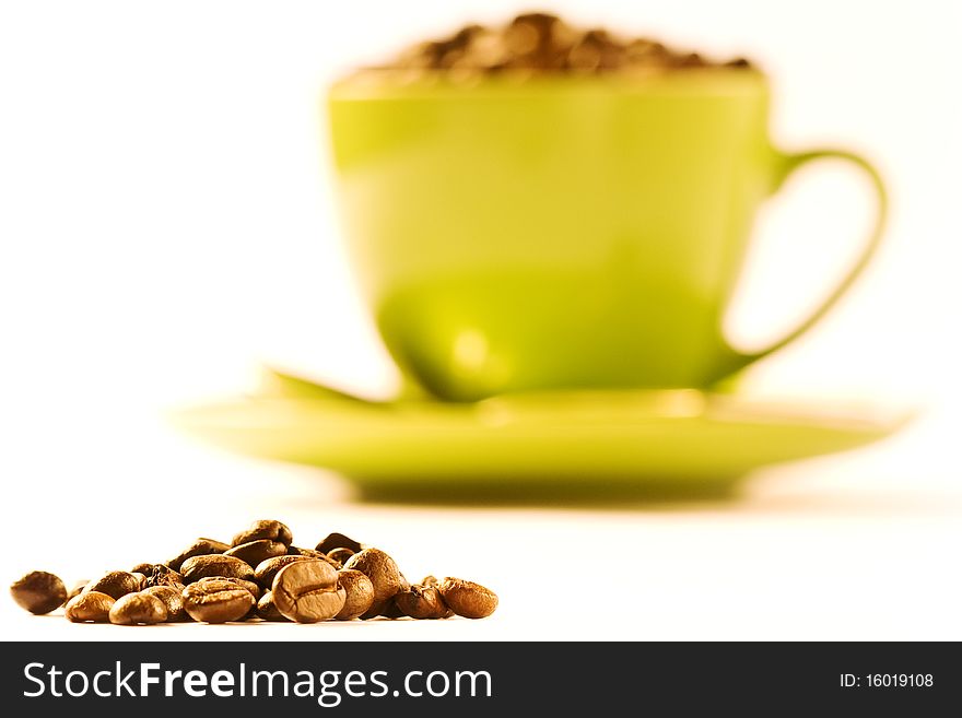 Green cup of coffee with much brown beans