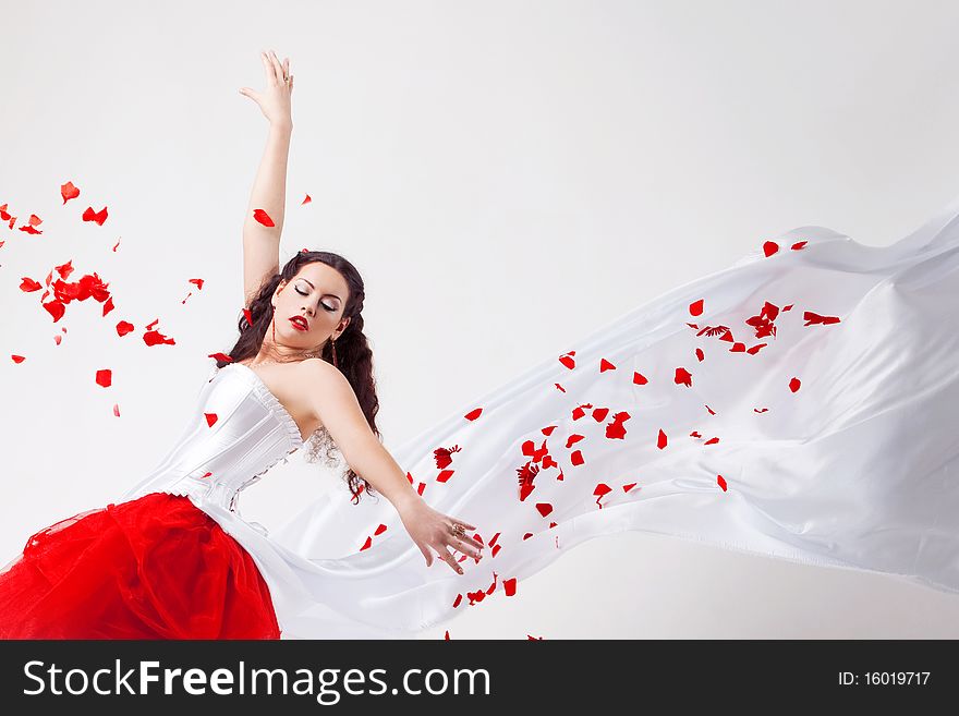 Young beautiful woman with petals of roses, on a white background