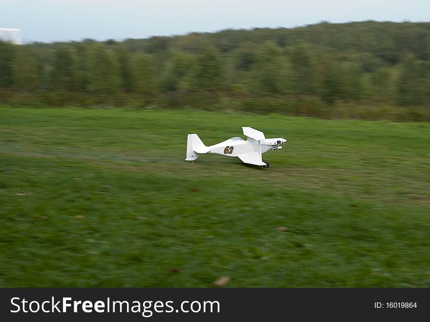 Radio-controlled airplain takes off on green grass