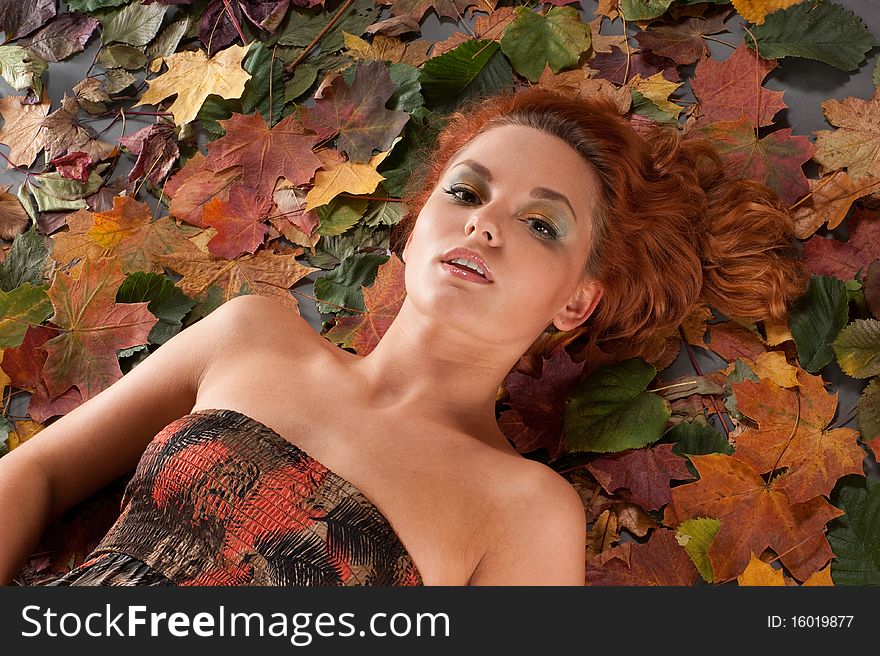 Autumn Image With A Girl Lying In Fallen Leaves