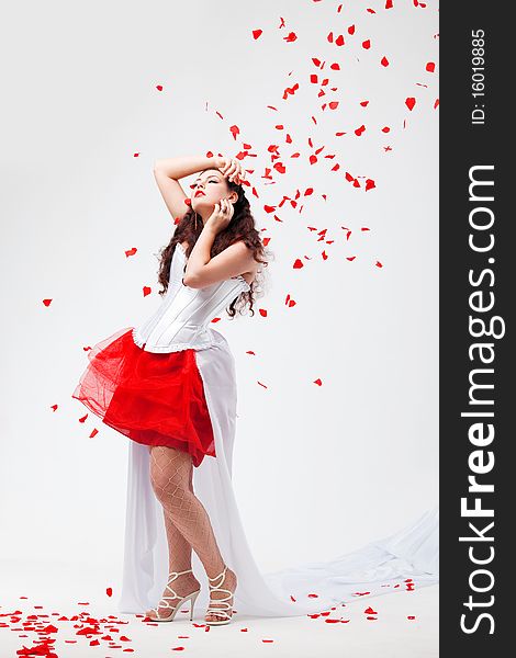 Young beautiful woman with petals of roses, on a white background