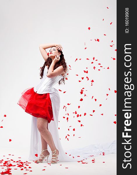 Young beautiful woman with petals of roses, on a white background