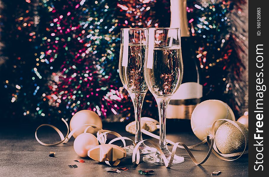Champagne in glass goblets a bottle of Christmas toys Serpentine stars sparkling festive background. New year concept.