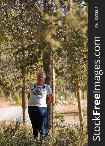 Casual portrait of happy mature woman against a background of pine trees. Casual portrait of happy mature woman against a background of pine trees.