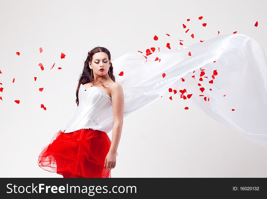 Young beautiful woman with petals of roses