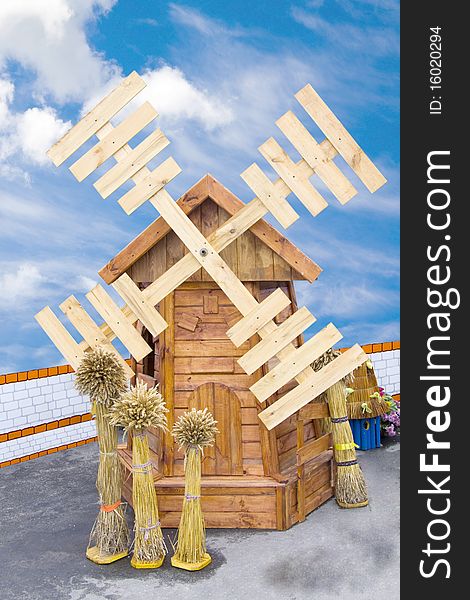 Wheat sheaves stand near a wooden mill on a white background. Wheat sheaves stand near a wooden mill on a white background