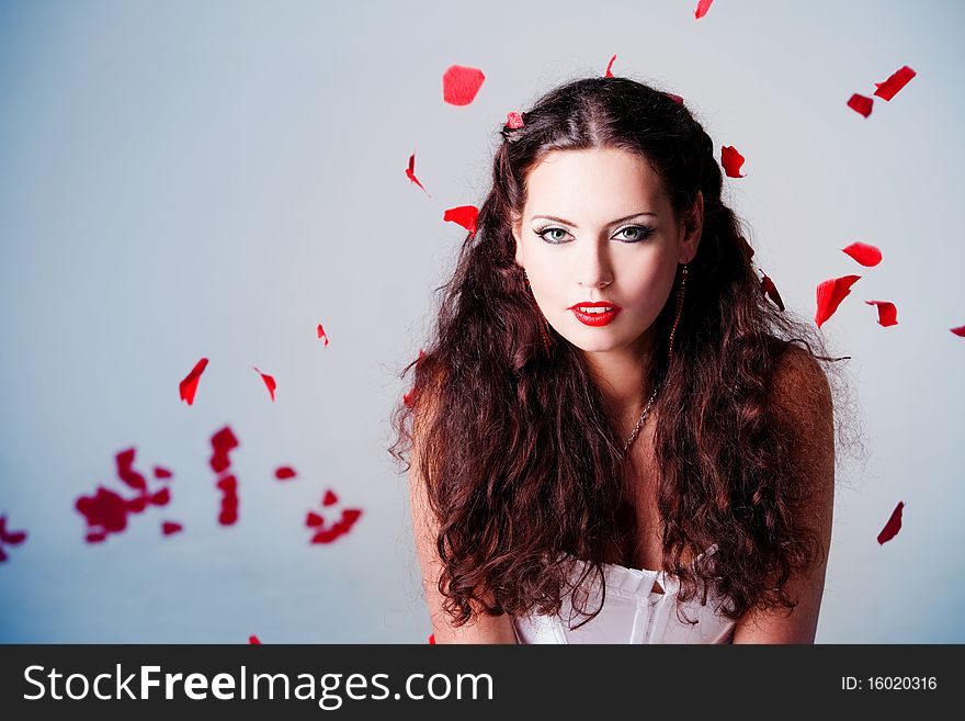 Young beautiful woman with petals of roses, on a white background