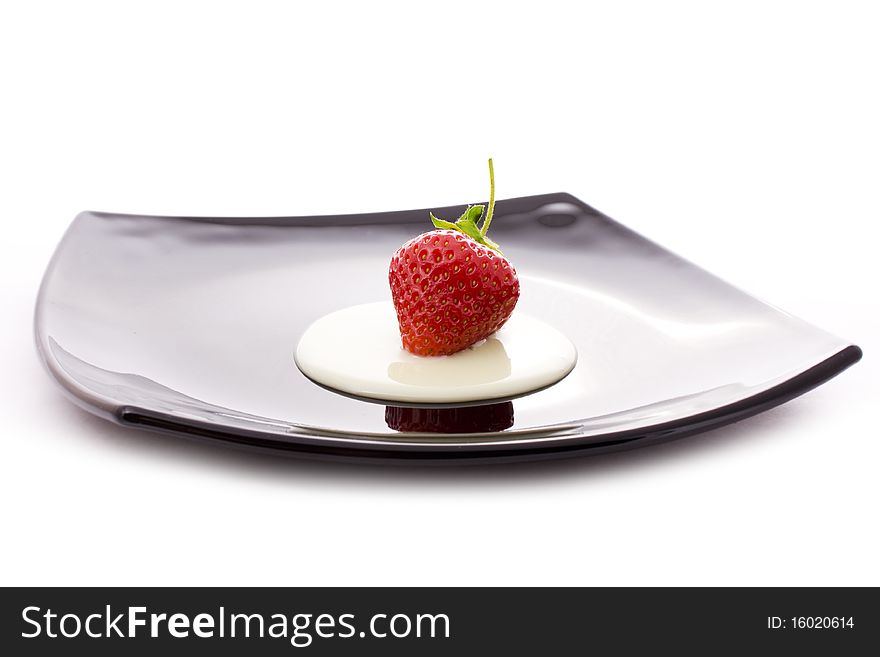 Red strawberry with cream on black plate isolated on white