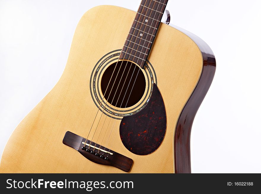 An acoustic guitar in a natural finish isolated against a white background. An acoustic guitar in a natural finish isolated against a white background