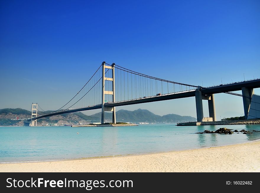 Bridge crossing the sea to an island under a clear blue sky just next to a white sand beach. Bridge crossing the sea to an island under a clear blue sky just next to a white sand beach.