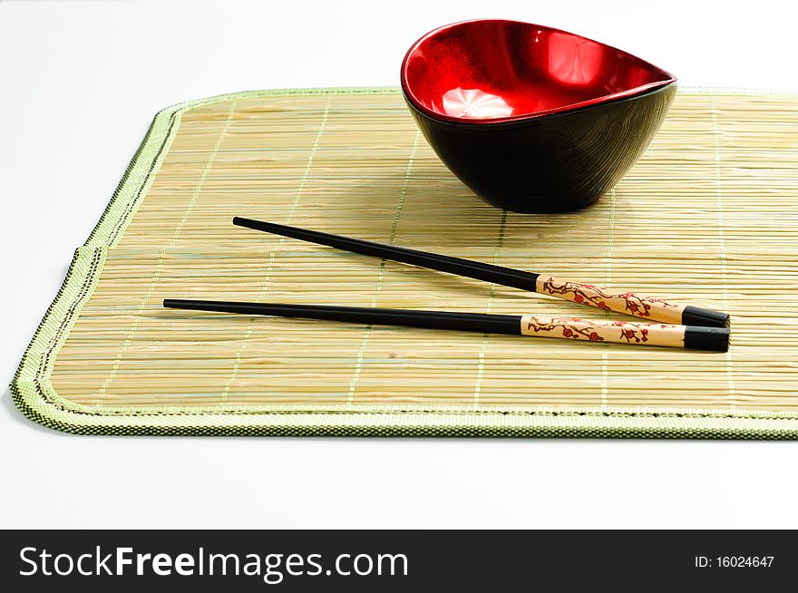 Two chop sticks and a red and black bowl. Two chop sticks and a red and black bowl
