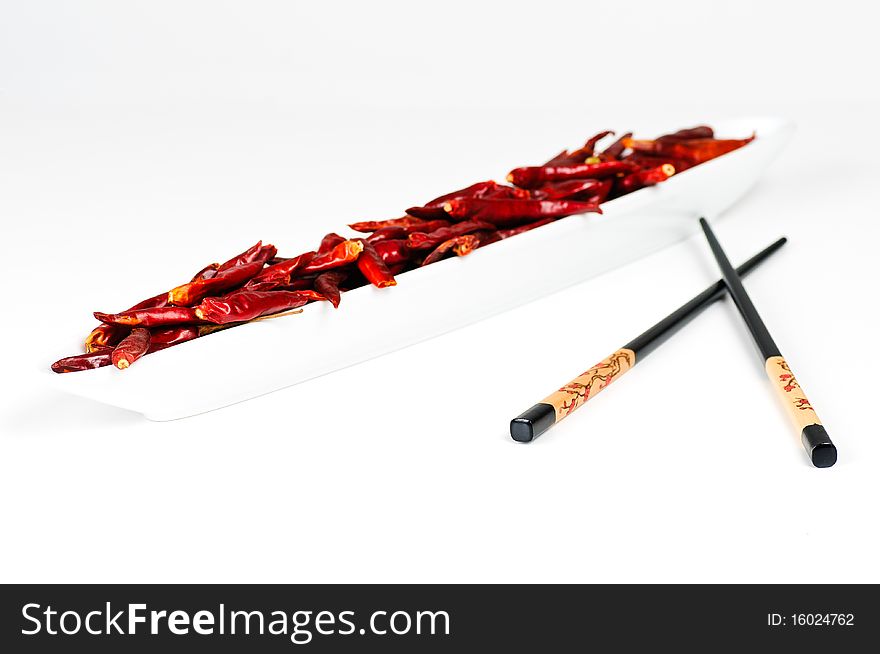 Two chop sticks and a bowl with dried chili fruits. Two chop sticks and a bowl with dried chili fruits