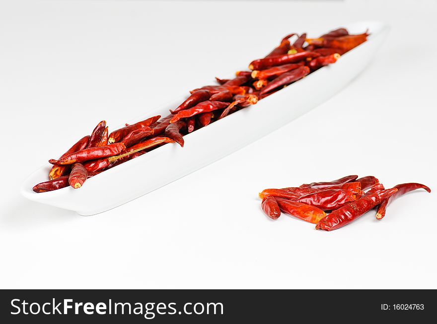 A bowl with some dried chili fruits with an additional pile next to it.