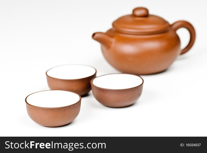 Clay tea cups with a tea pot in the background