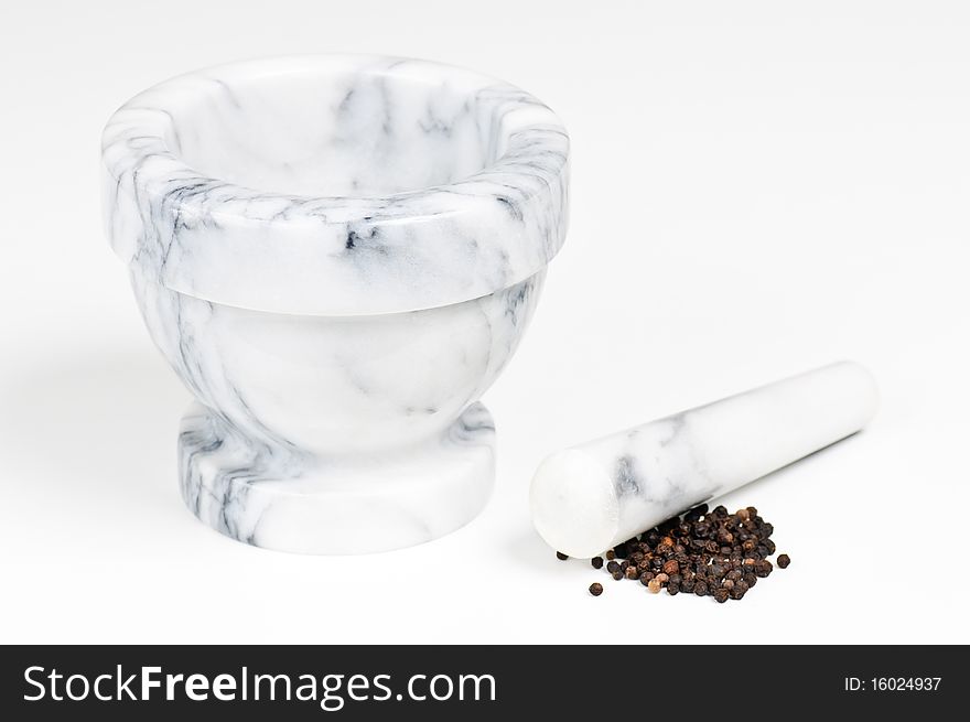 A marble mortar with pestle with some dried black pepper. A marble mortar with pestle with some dried black pepper