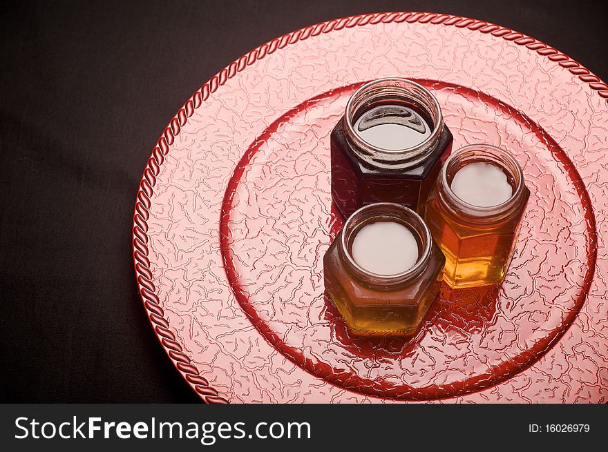 Jars filled with colorful jam on top of a red decorative plate