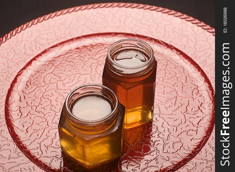 Jars filled with colorful jam on top of a red decorative plate