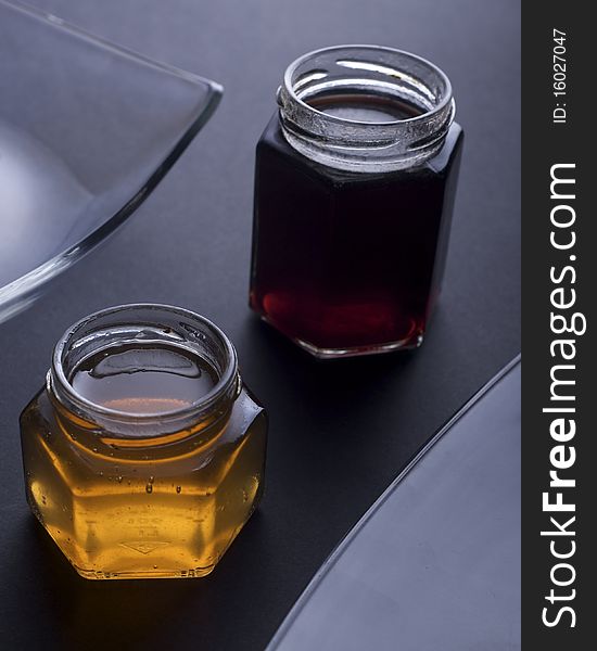 Jars filled with colorful jam shot in low key with modern glass