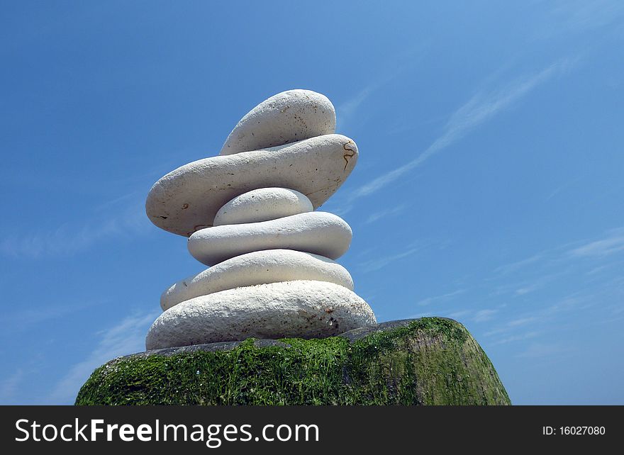Pile of stones on wooden post against blue sky. Pile of stones on wooden post against blue sky