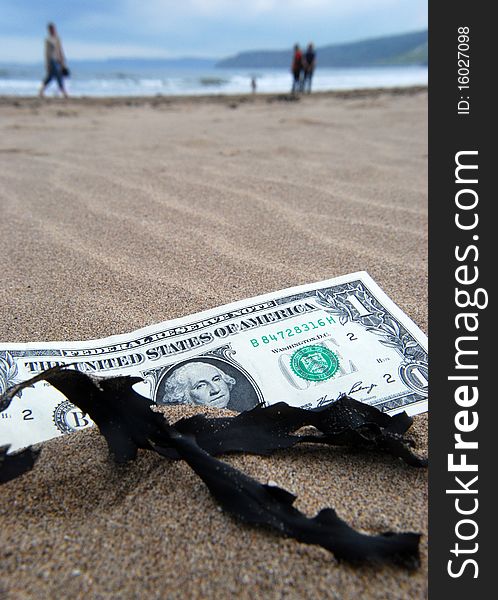 US Dollar banknote partially buried on beach. US Dollar banknote partially buried on beach